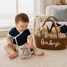 Baby wearing a navy Lovingly Organics Samurai Tee while exploring a fabric book beside a luxury baby gift basket.
