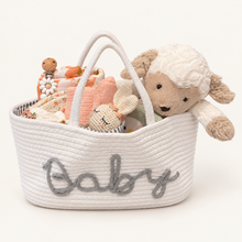 Hand-arranged floral baby gift basket with blush romper, poppy swaddle, bunny accessories and plush lamb.